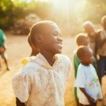 A group of young children standing on top of a dirt field